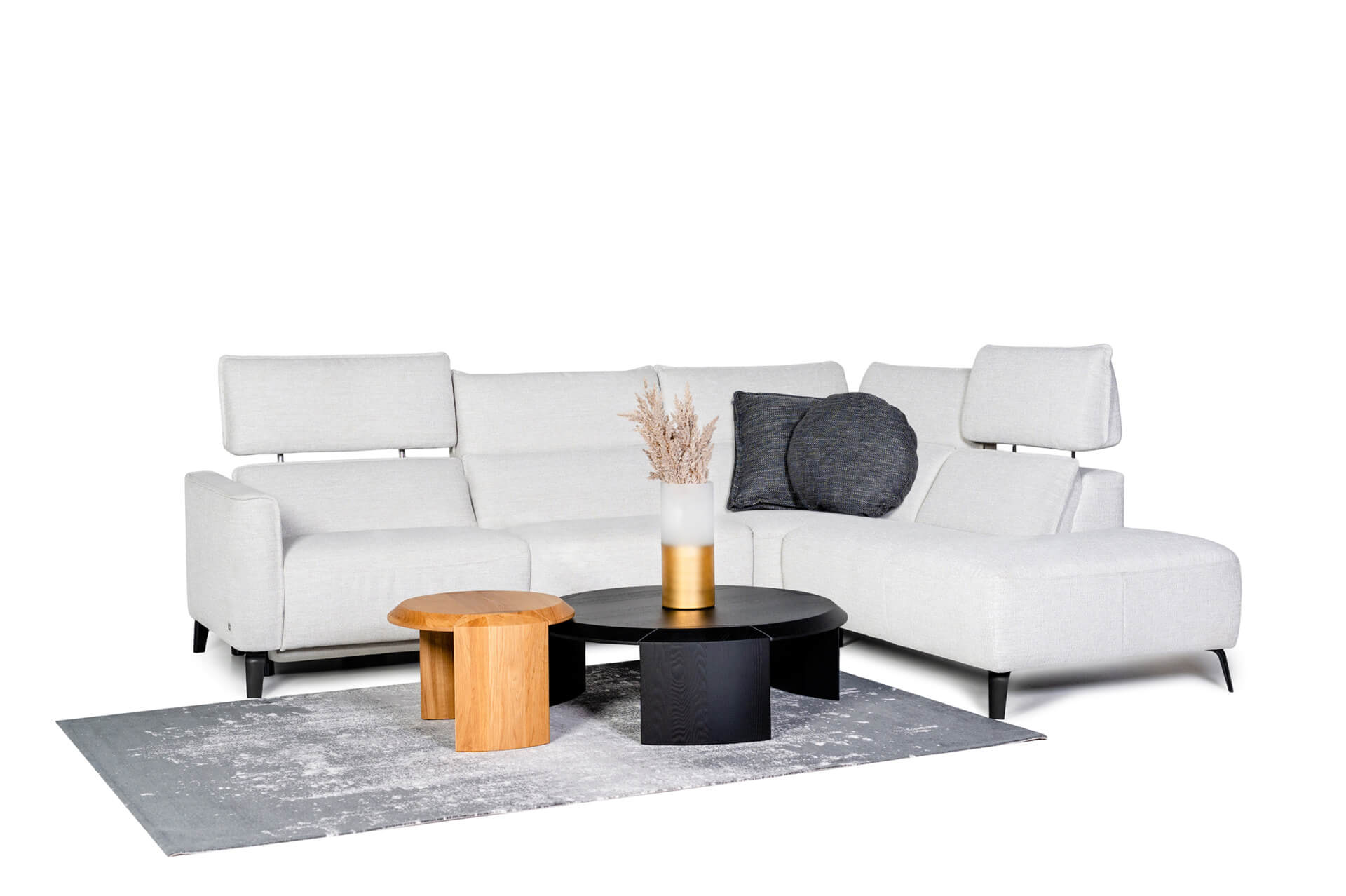 Odkryj Imperia - Wygodny narożnik z tkaniną zmywalną i relaksem No Gravity. To biała sofa modułowa, kt&oacute;ra wyr&oacute;żnia się w tym nowoczesnym salonie, uzupełniona ciemnoszarą poduszką, okrągłym czarnym stolikiem kawowym, drewnianym stolikiem bocznym, wszystko na szarym dywanie.